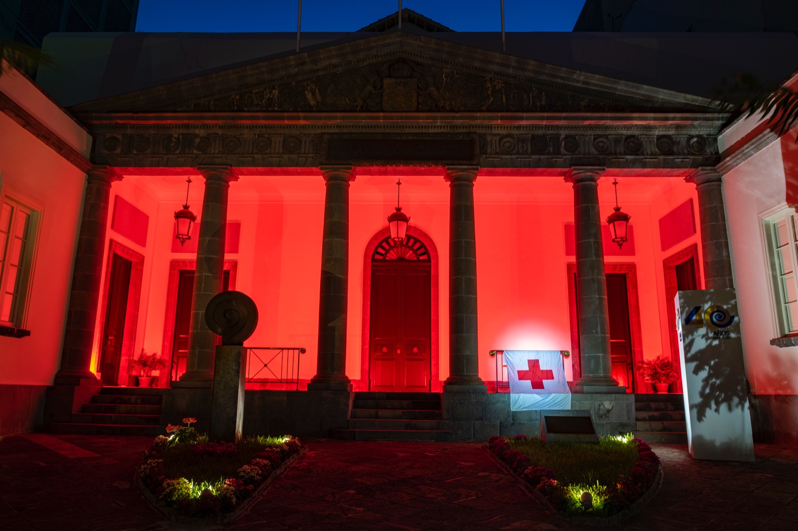 Fachada iluminada de color rojo conmemorando el Día Mundial de la Cruz Roja y de la Media Luna Roja