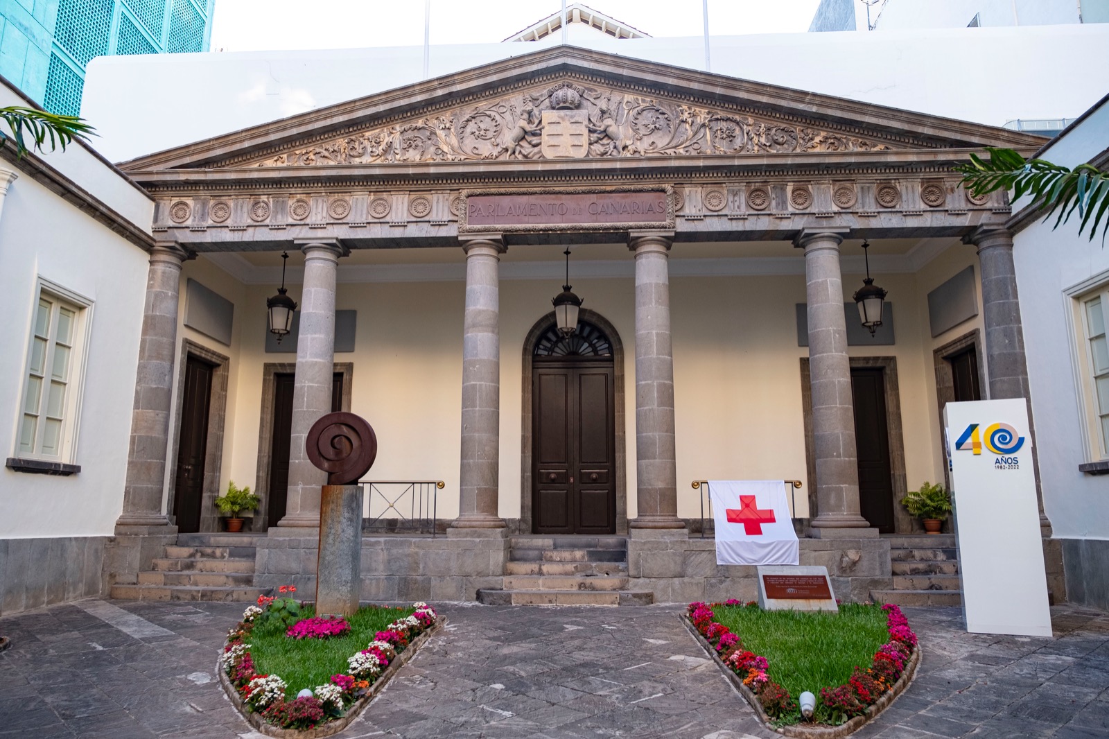 La fachada del Parlamento de Canarias luce la bandera de Cruz Roja